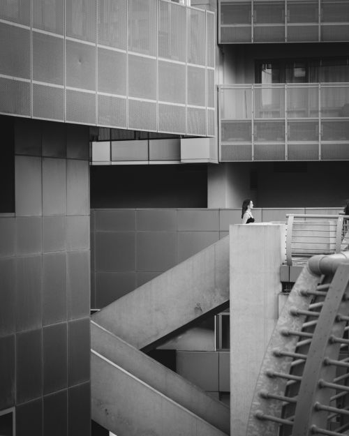 Free A minimalist and modern urban architectural scene featuring a lone woman on stairs. Stock Photo