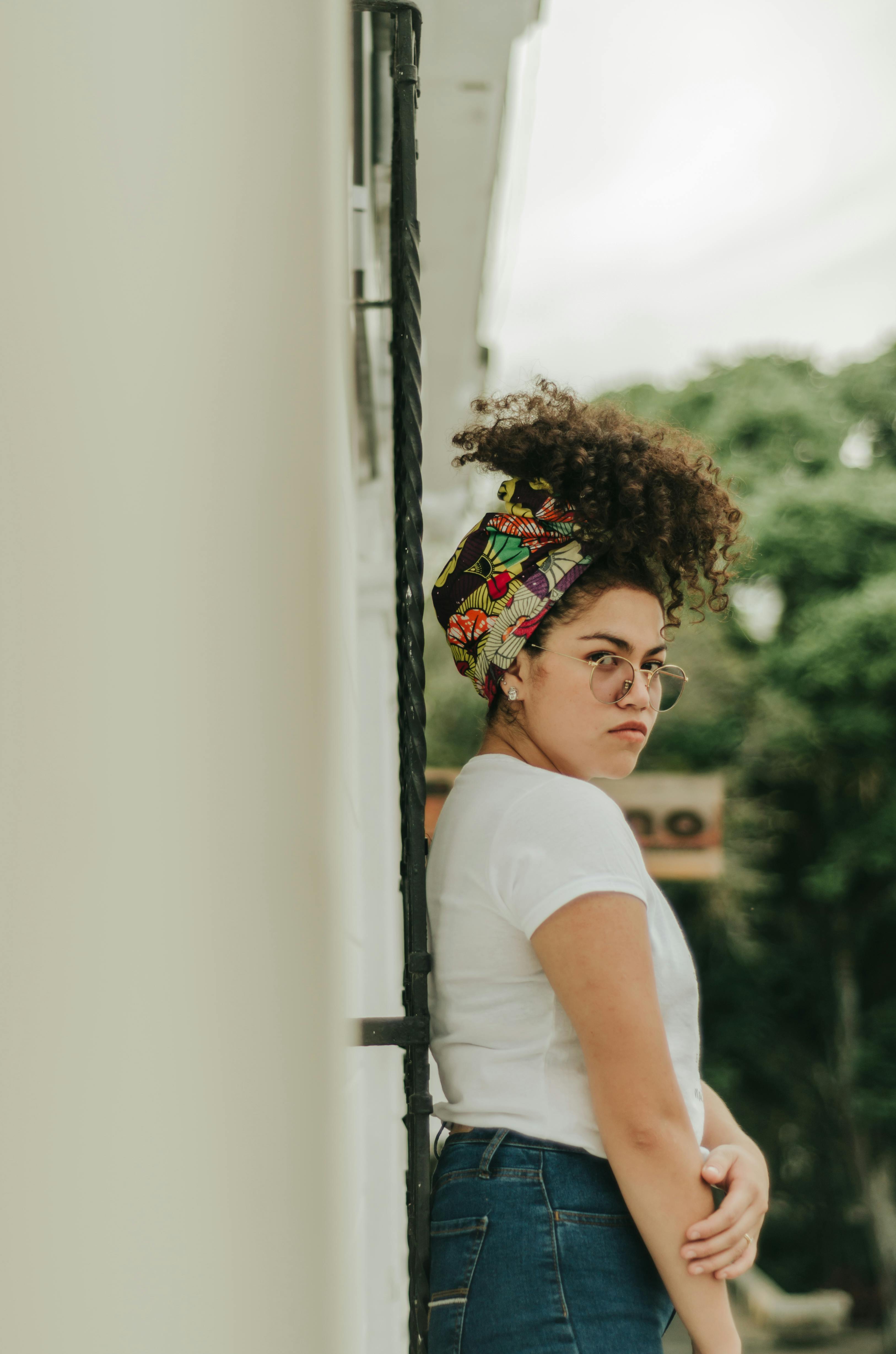 A woman stands outdoors in Colombia with a colorful headscarf and casual attire, showcasing modern fashion style.