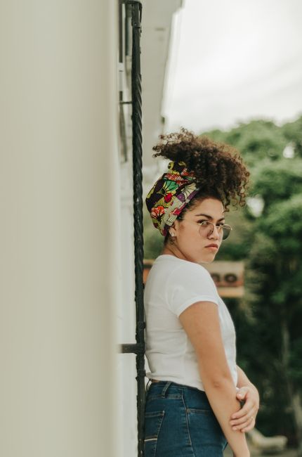 A woman stands outdoors in Colombia with a colorful headscarf and casual attire, showcasing modern fashion style.