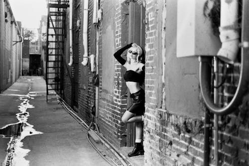 A woman leaning against a wall in a alley