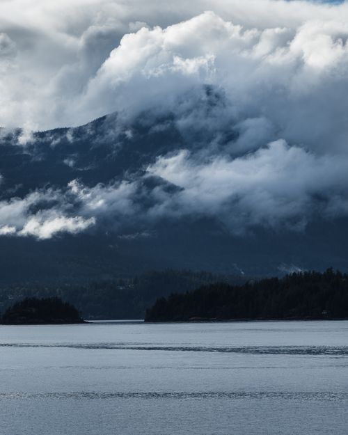 Free Tranquil scene of a lake with clouds drifting over a misty mountain range. Stock Photo