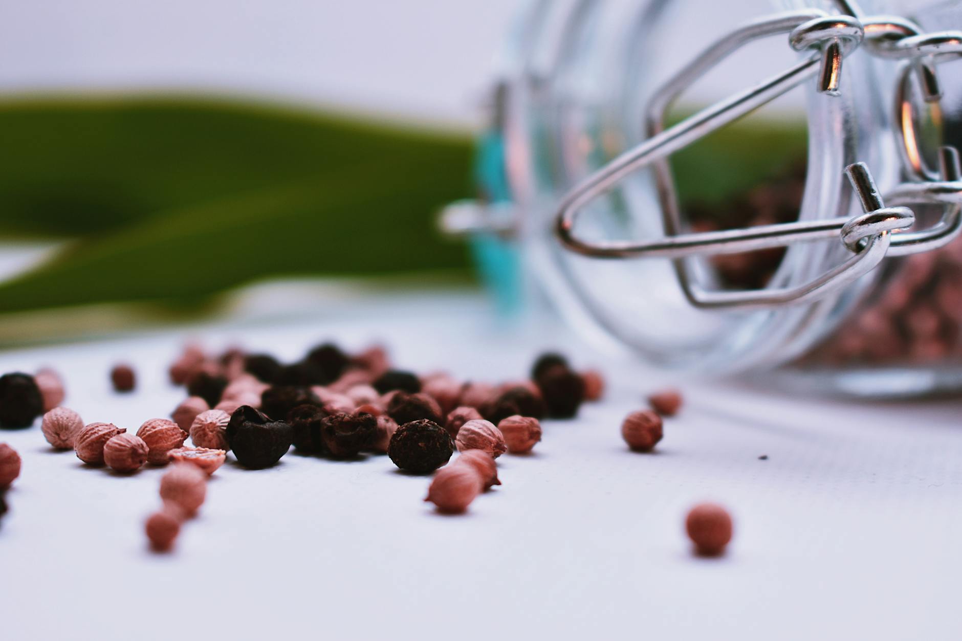 Colorful peppercorns spilled from a glass jar creating a vibrant culinary scene.