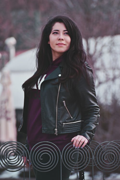 Photo of Woman in Black Leather Jacket Holding Gray Metal Railings