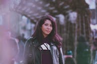 在繁忙的街道上，一位穿着皮夹克的时尚女人正在户外摆姿势