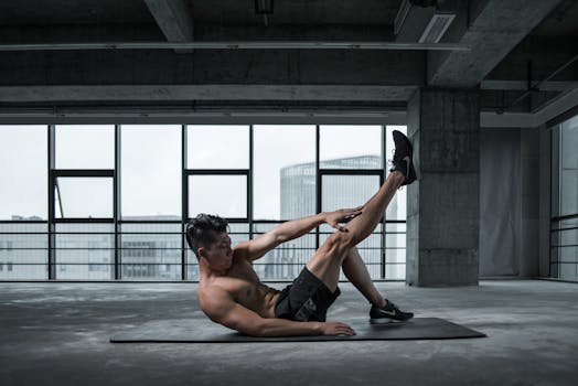 A shirtless man performs an ab workout on a yoga mat in an urban indoor gym setting.