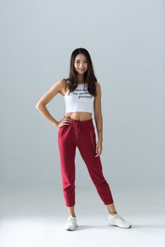 一位迷人的年轻女子穿着红色慢跑鞋，在工作室里自信地摆出展现风格的姿势