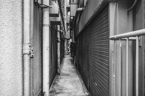 A black and white photo of a narrow alley