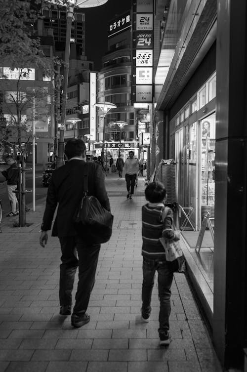 A man and a child walking down a street at night