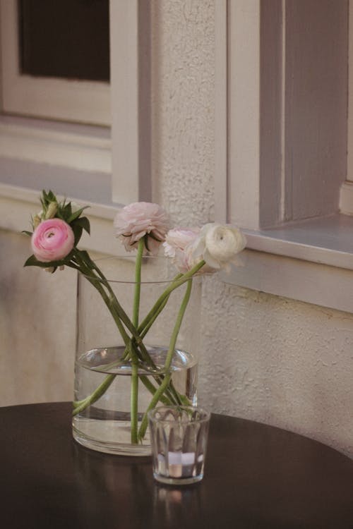 A vase with flowers on a table next to a window