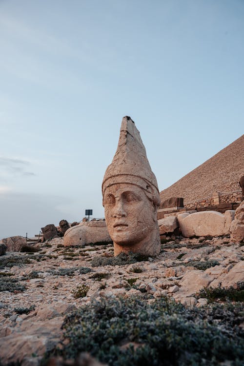 The head of a statue is sitting on top of a rock
