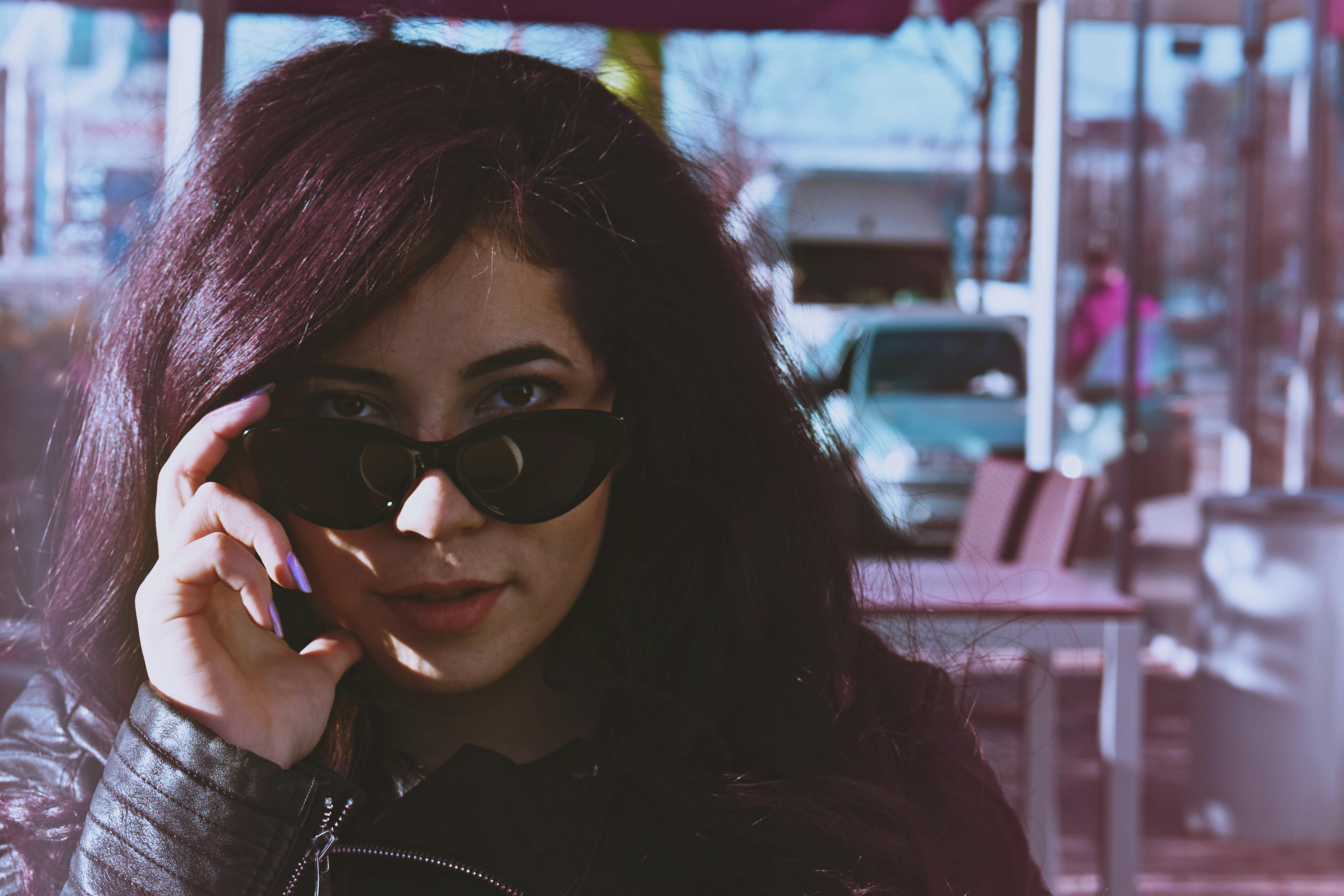 一位时尚的女人在户外咖啡馆戴着太阳镜和皮夹克摆姿势