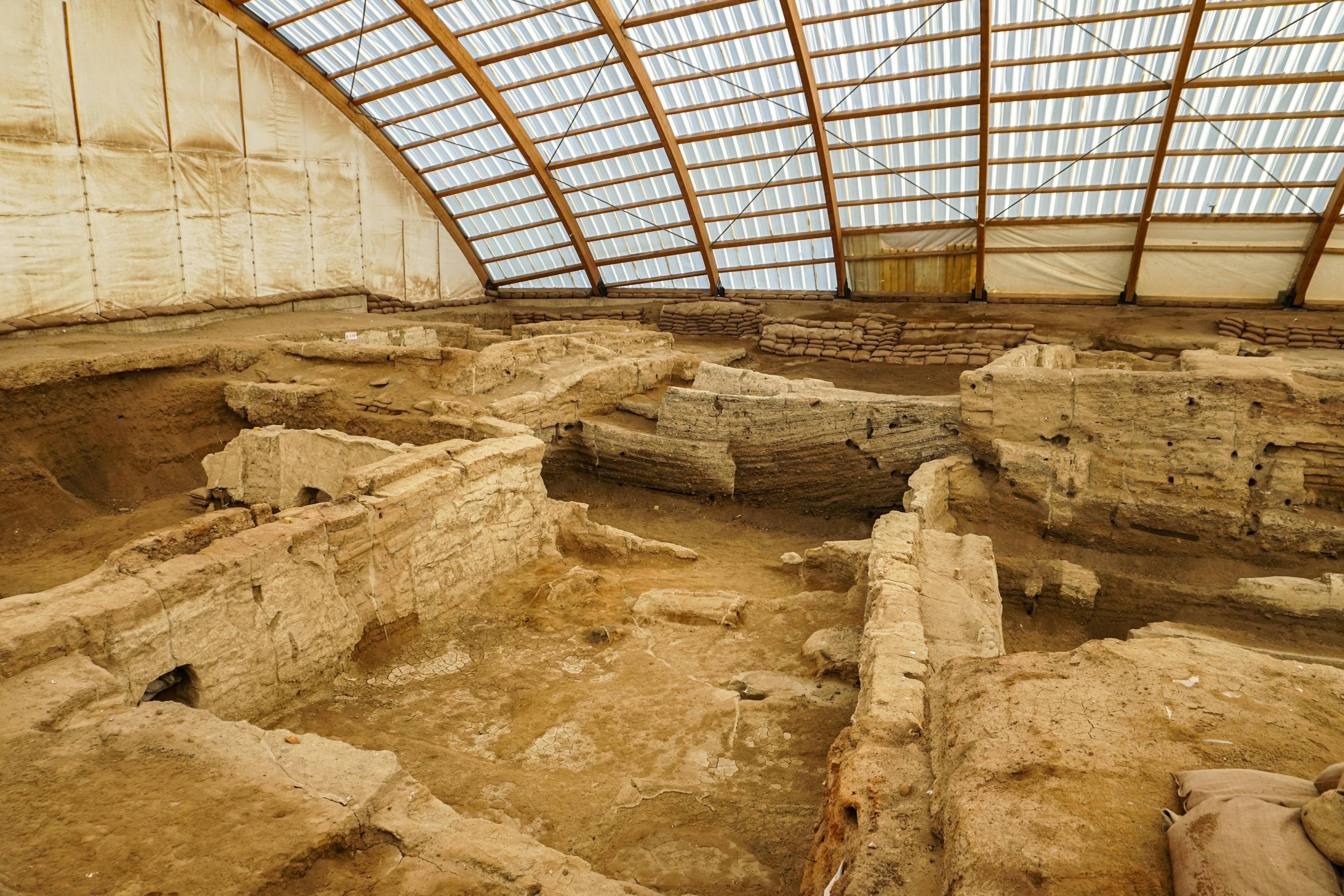 Çatalhöyük Neolithic site Turkey with ancient mudbrick ruins, archaeological excavation trenches, and golden Anatolian plains under soft morning light