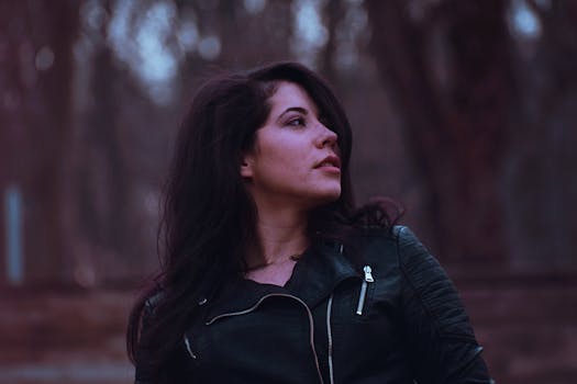 一位穿着黑色皮夹克的女人在户外环境中遥望的迷人肖像