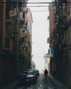 Moody urban street scene in Barcelona, Spain, showing pedestrians and parked vehicles.