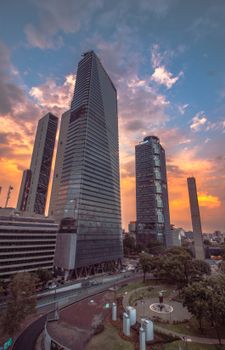 Modern skyscrapers in Mexico City's skyline at sunset, featuring iconic landmarks.