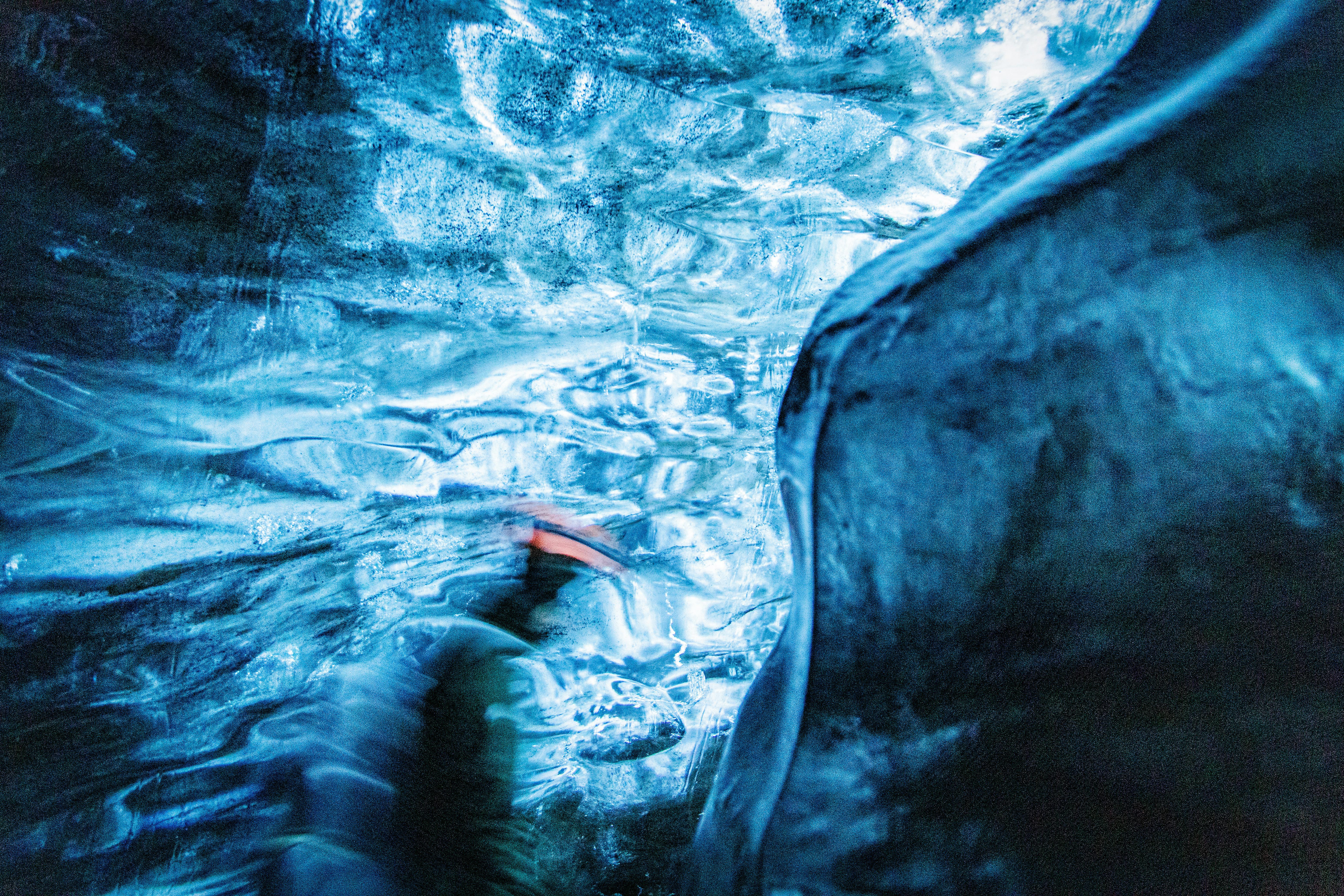 A mesmerizing view of an ice cave in Iceland with a blurred figure, creating an abstract artistic effect.