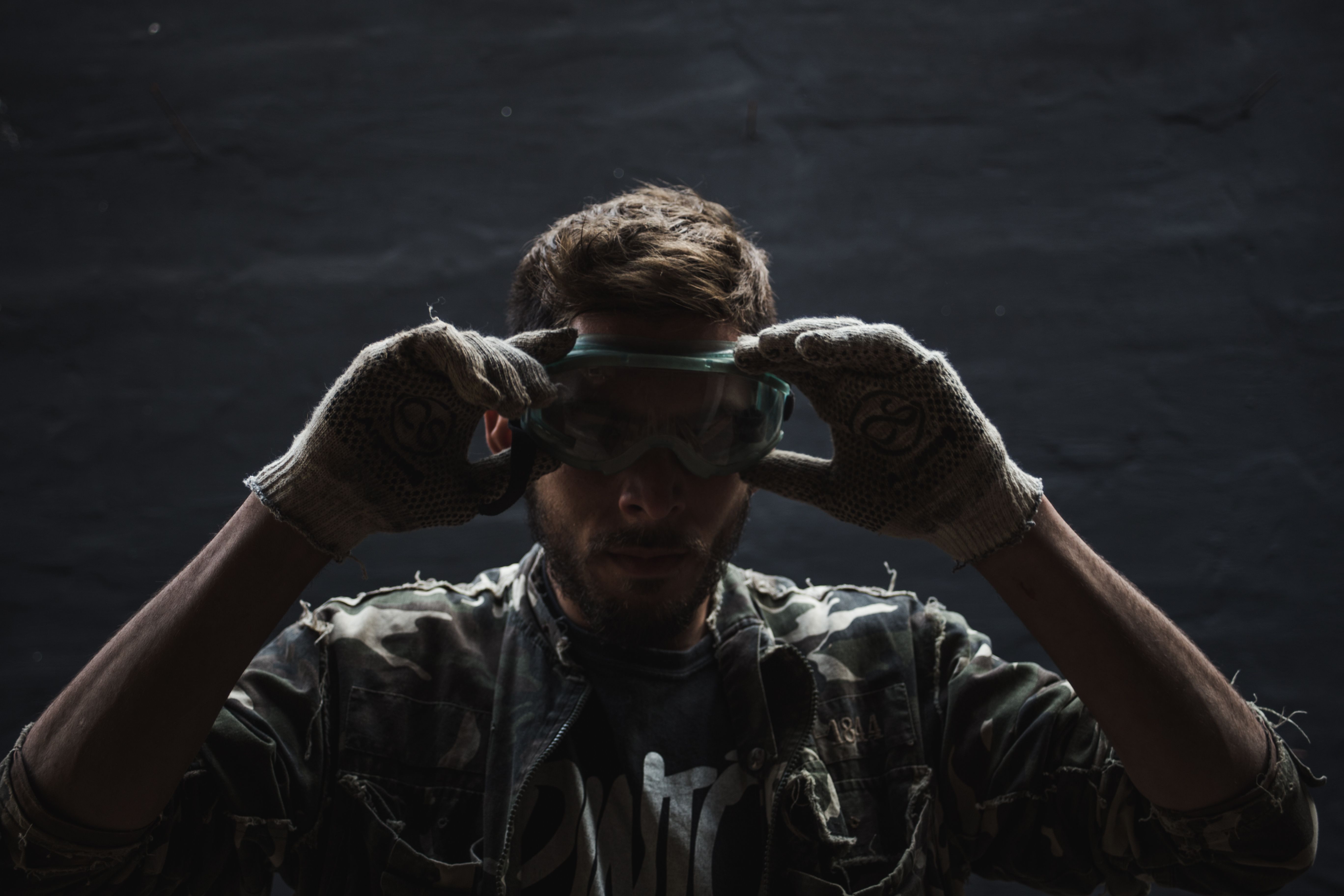 homeowner wearing protective gloves and goggles while inspecting a water heater