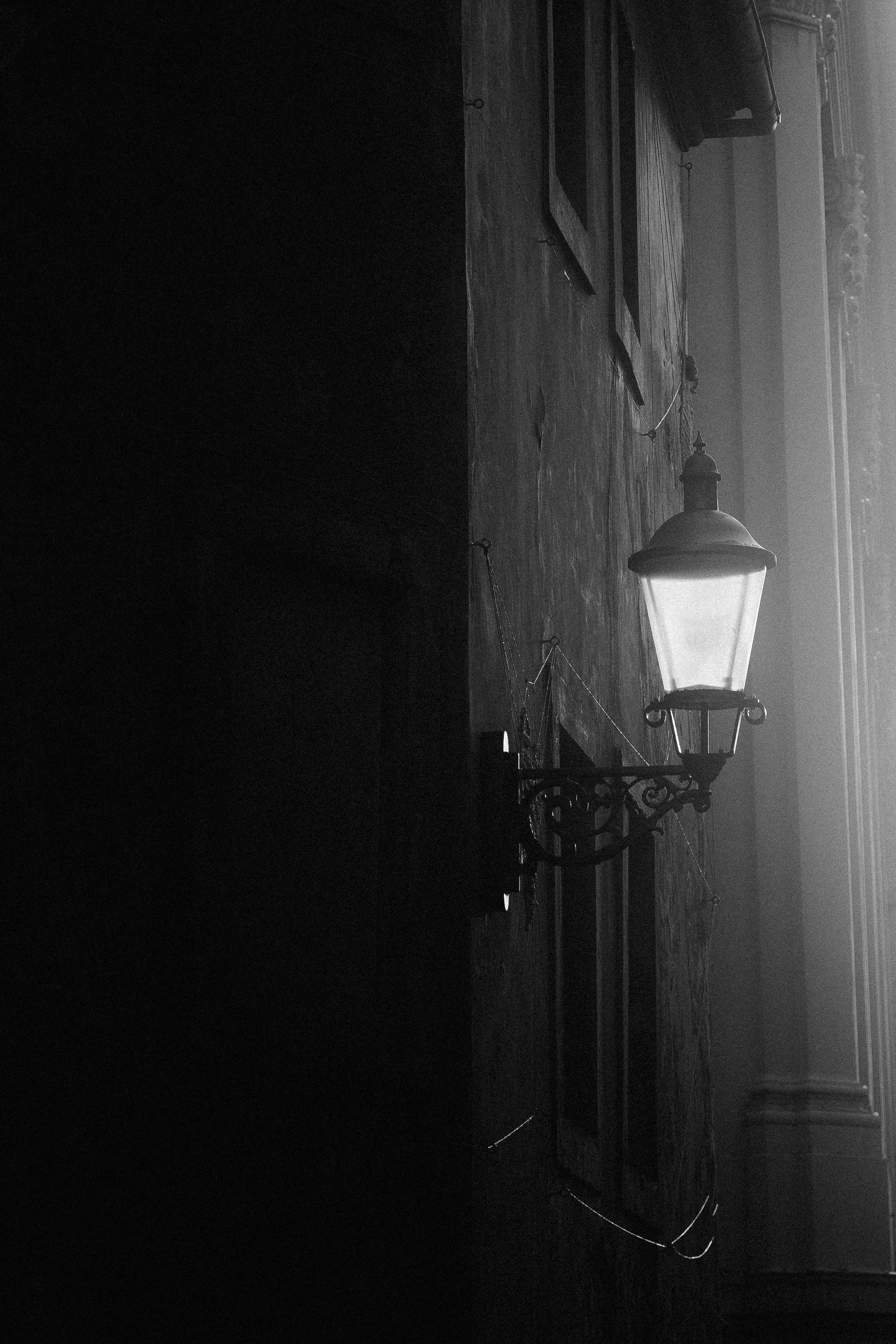 Atmospheric black and white photo of a street lantern casting light on a town facade in Zittau, Germany.
