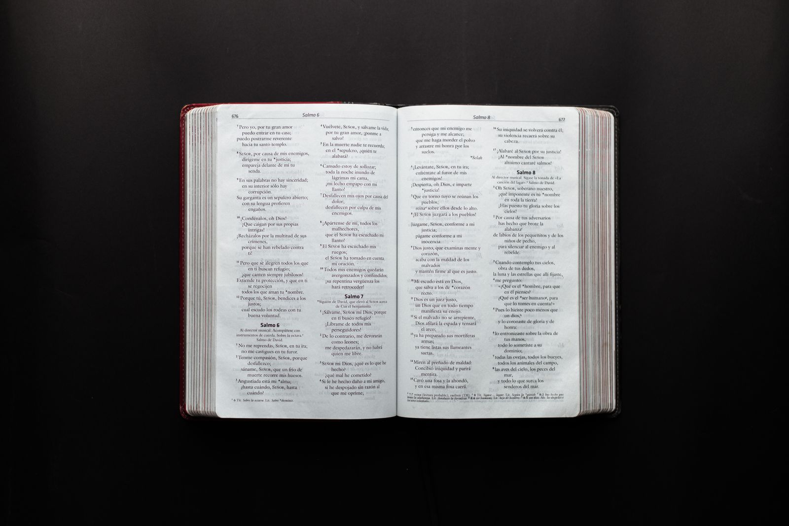 An open Bible resting on a dark surface, lit softly.