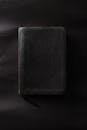 一本合着的黑色皮革装帧书放在纯黑色的表面上