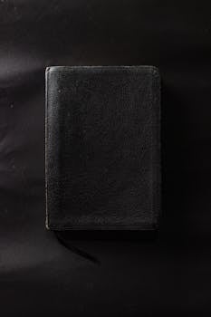 一本合着的黑色皮革装帧书放在纯黑色的表面上