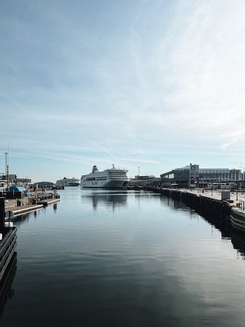 A boat docked at a dock with a large cruise ship