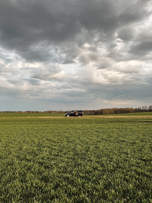 A tractor is parked in a field under a cloudy sky