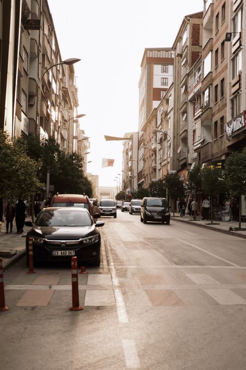Free A vibrant city street bustling with cars and pedestrians during sunset in an urban setting. Stock Photo