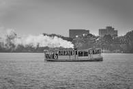 在德国汉堡风景优美的水道上，一艘热气腾腾的渡轮在黑白照片中航行