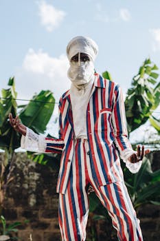 Stylish man in vibrant suit poses outdoors against banana leaves.