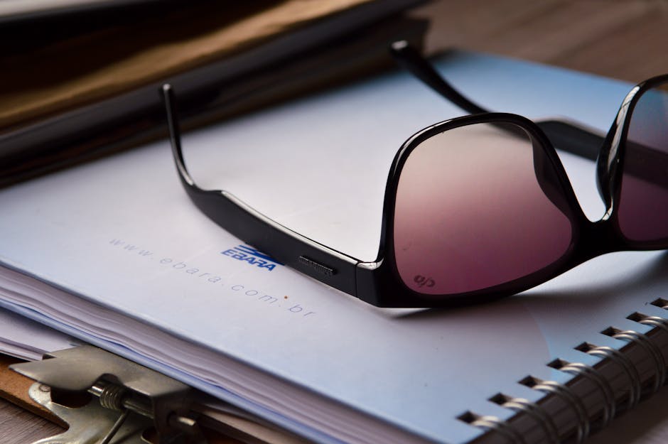 Close-up of sunglasses on a notebook with a clipboard, ideal for office or lifestyle topics.