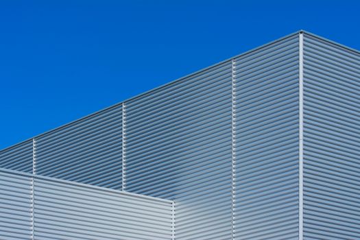 Minimalist facade of modern building with metallic texture against a blue sky.