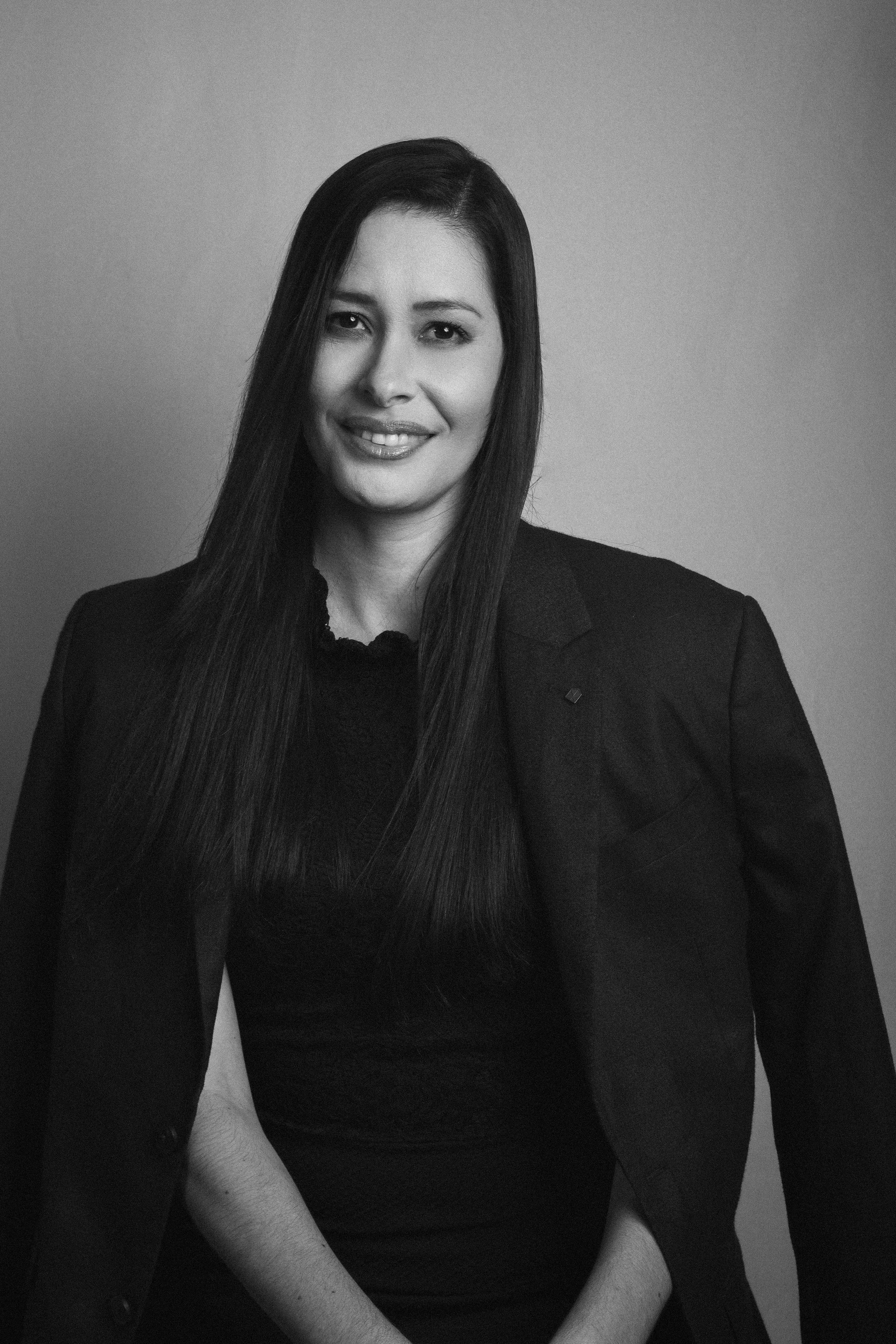 Sophisticated black and white portrait featuring a smiling woman in a studio setting.
