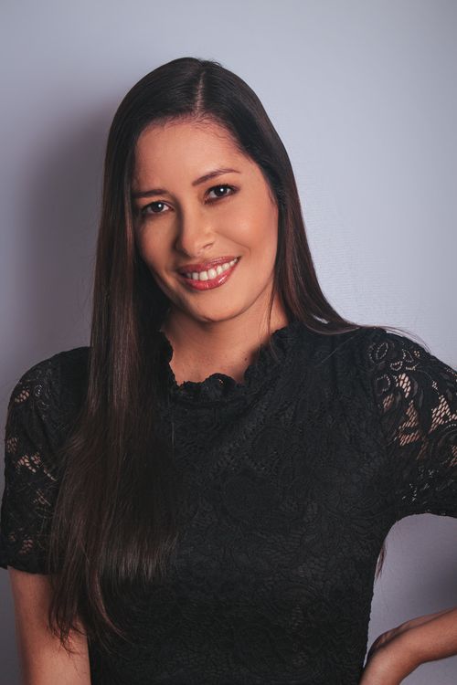 Free Close-up image of a young woman wearing a black dress, smiling confidently against a light background. Stock Photo
