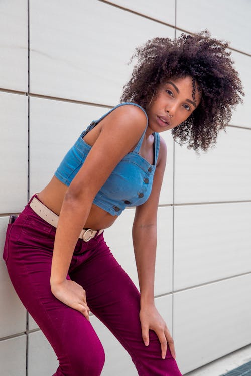 Free Photo of Woman in Blue Denim Crop Top and Purple Jeans Leaning at Tiled Wall Stock Photo