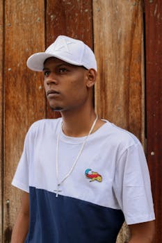 圣保罗，一名身穿休闲装、戴着帽子的男子，站在木制背景前的肖像