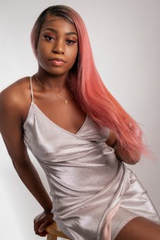 一位粉红色头发的优雅女子在时尚工作室的木椅上摆姿势