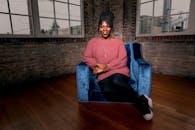 一位穿着舒适毛衣的非洲裔美国妇女坐在别致的扶手椅上，热情地微笑着