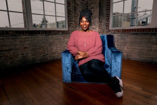 一位穿着舒适毛衣的非洲裔美国妇女坐在别致的扶手椅上，热情地微笑着