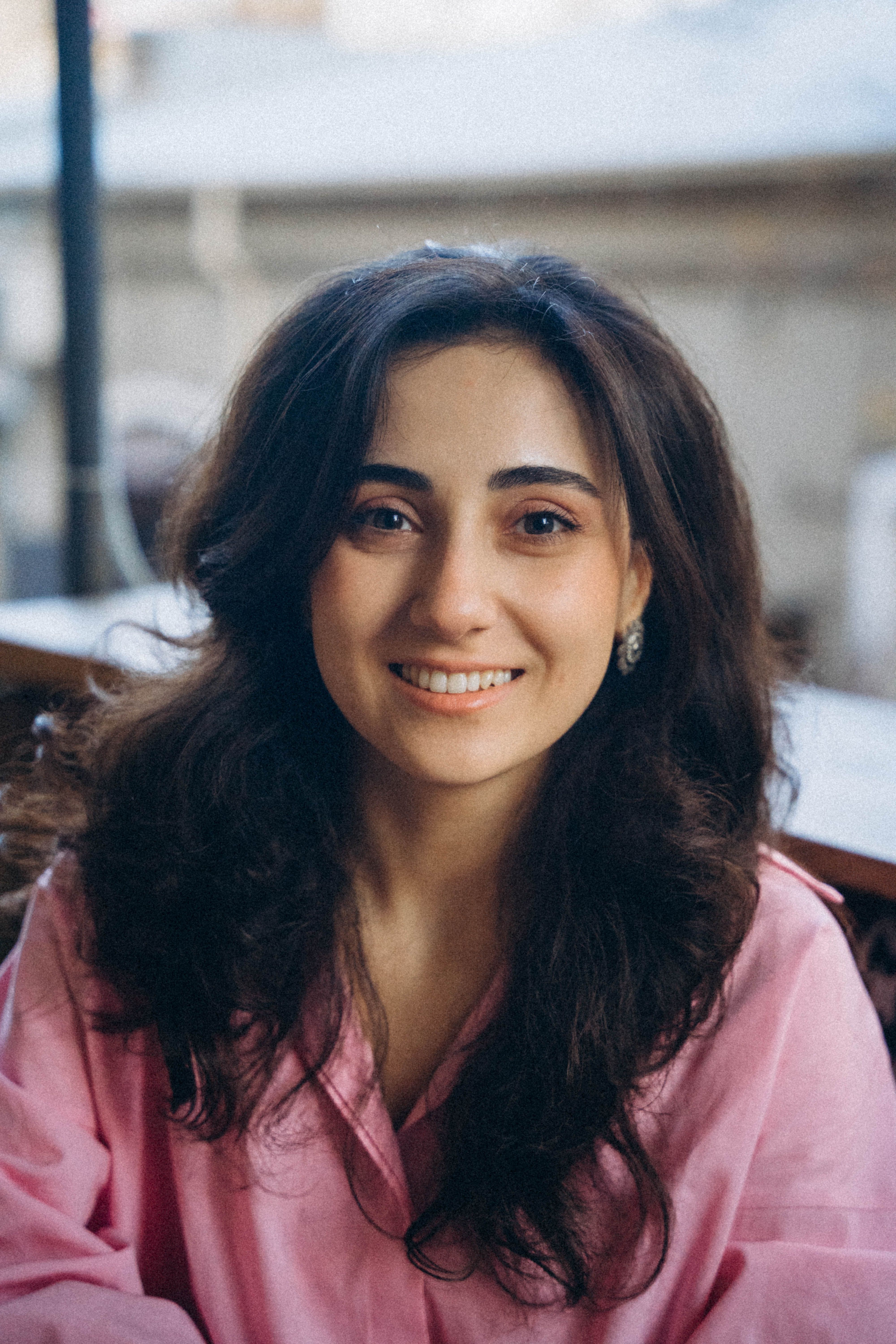 A cheerful young woman in Baku, Azerbaijan, smiling warmly in this outdoor portrait.