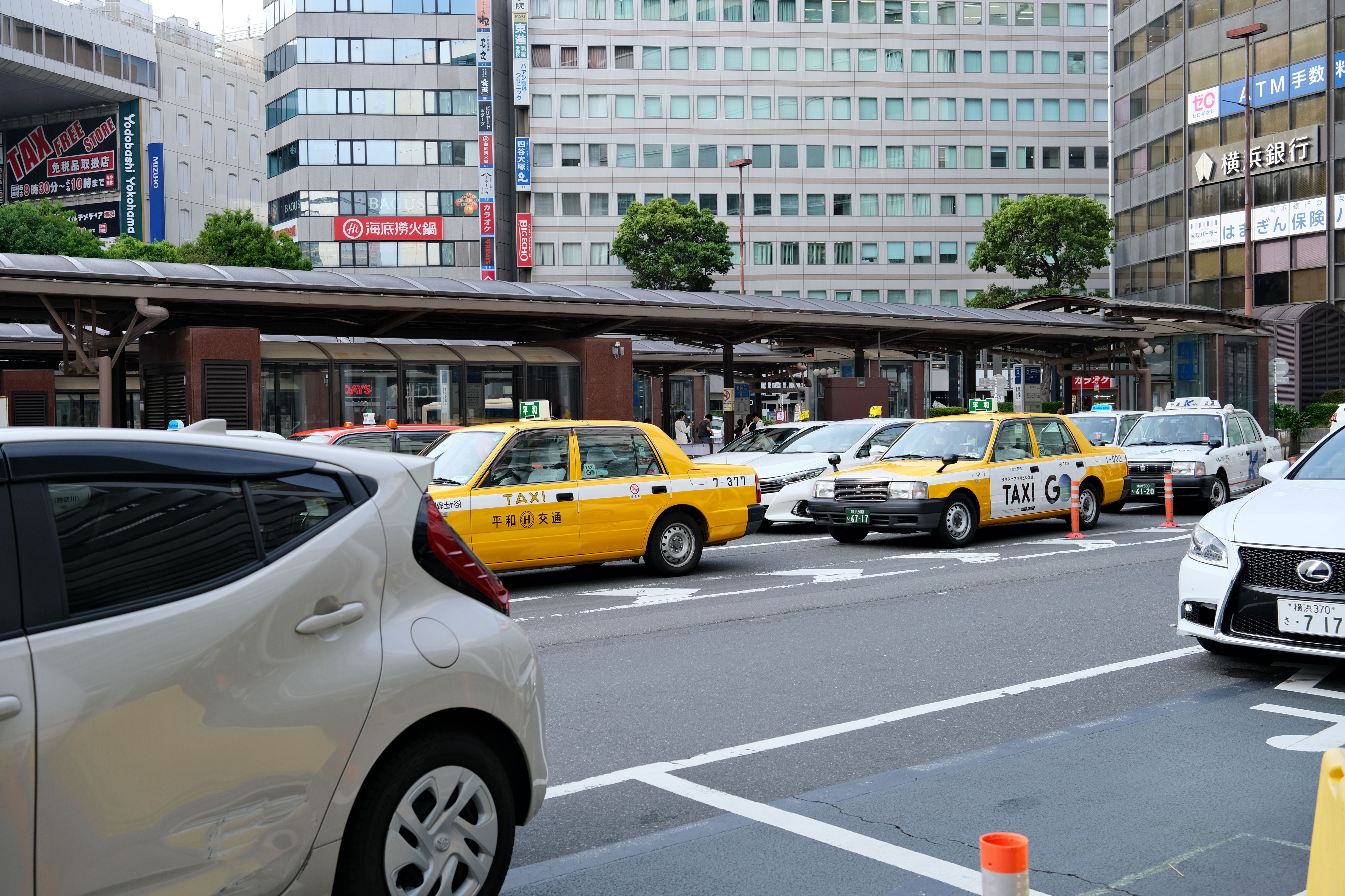 横浜、日本の黄色いタクシーと現代的な建物の都市風景。
