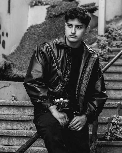 A man in a leather jacket sitting on some steps