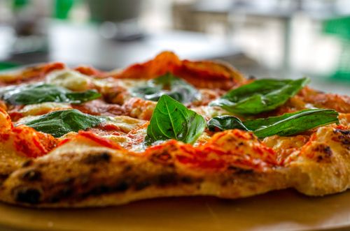 Free Close-up shot of fresh basil leaves topping a classic Italian pizza with melted cheese and tomato sauce. Stock Photo