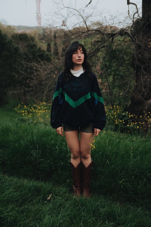 A woman in a sweater and boots standing in a field