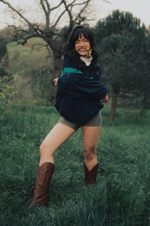 A woman in shorts and boots posing in a field