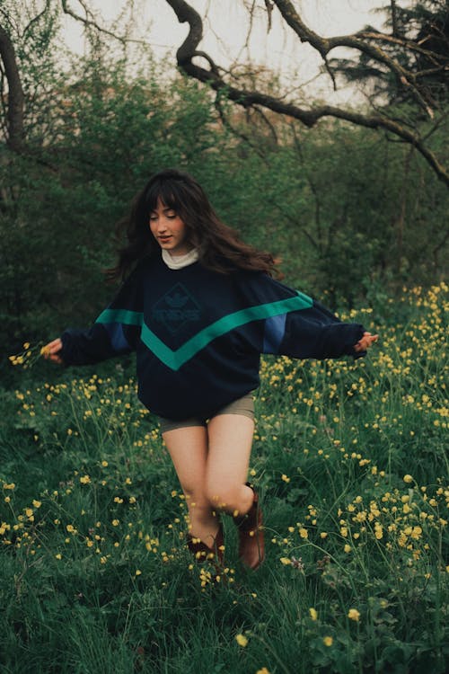 A woman in a sweater and boots is running through a field