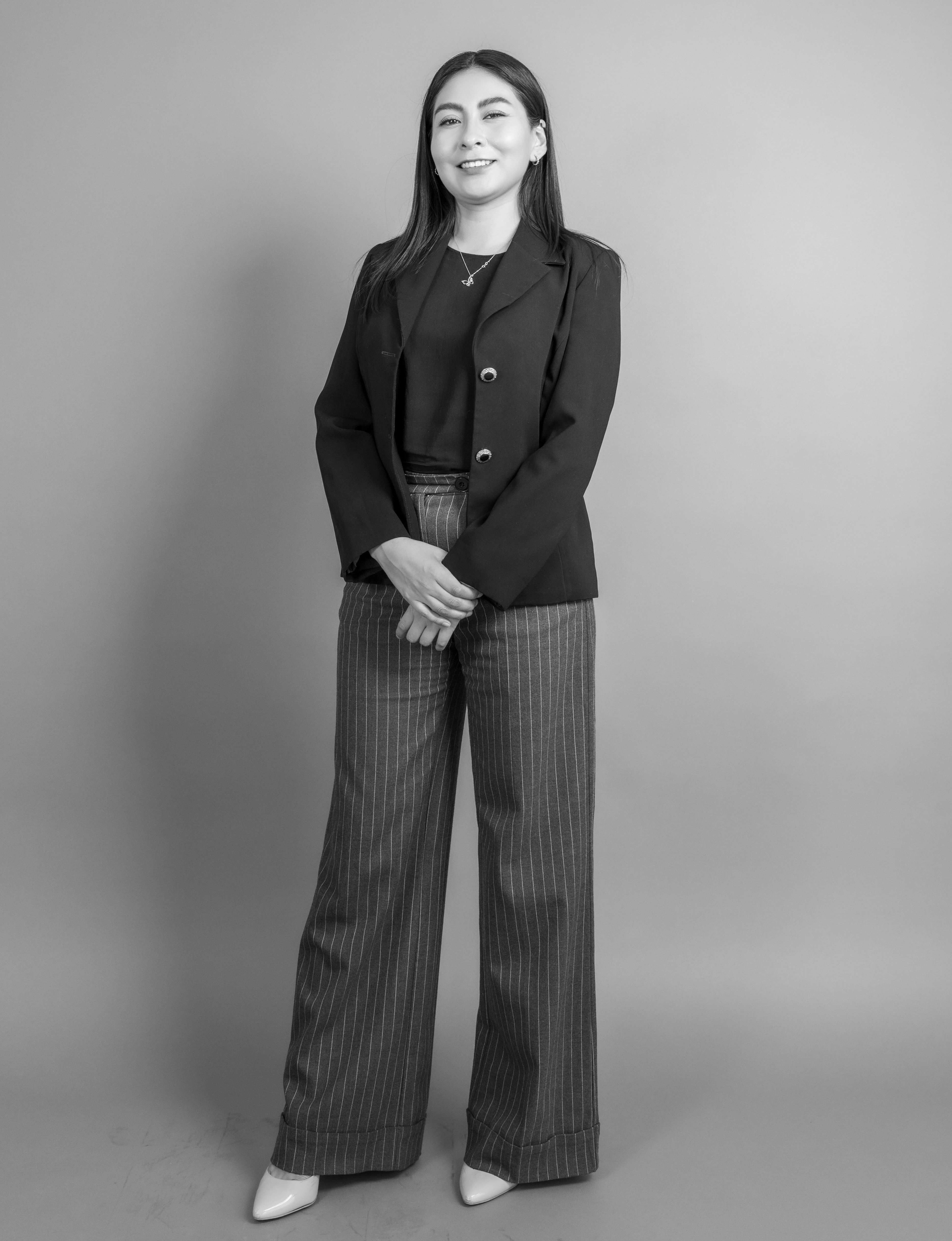 Elegant black and white portrait of a smiling woman standing in a studio setting.