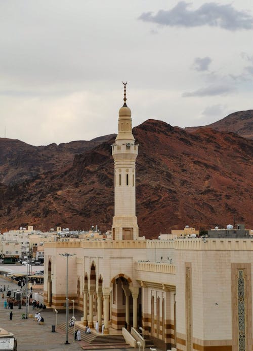 A mosque in the middle of a desert with mountains in the background