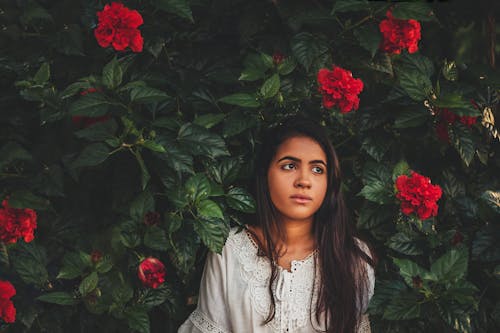 Woman Standing in Front on Red Petaled Flowers