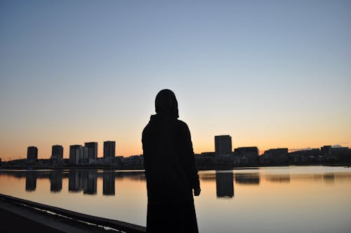 Silhouette Di Una Persona In Piedi Di Fronte A Un Corpo D'acqua